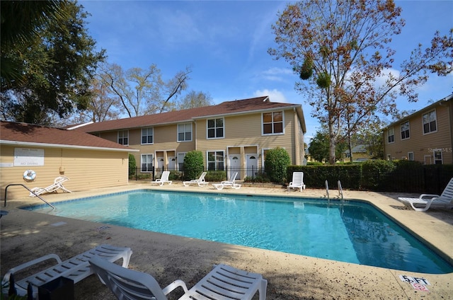 community pool with a patio and fence