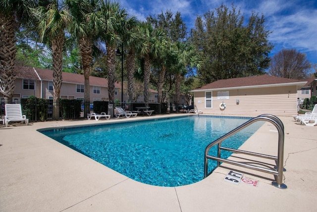 pool with a patio area and fence