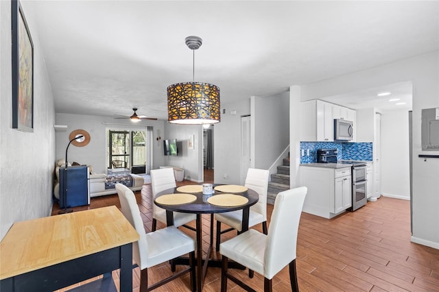 dining space with light wood-style flooring, stairs, baseboards, and a ceiling fan