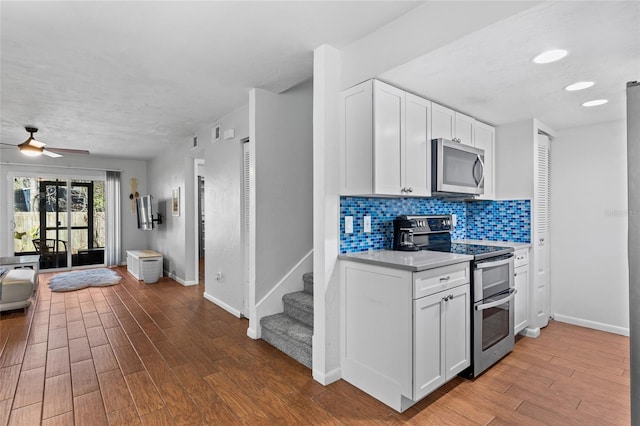 kitchen with light wood-style flooring, stainless steel appliances, white cabinetry, light countertops, and backsplash