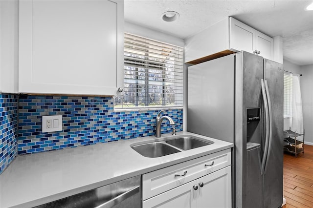 kitchen featuring white cabinets, decorative backsplash, stainless steel appliances, and a sink