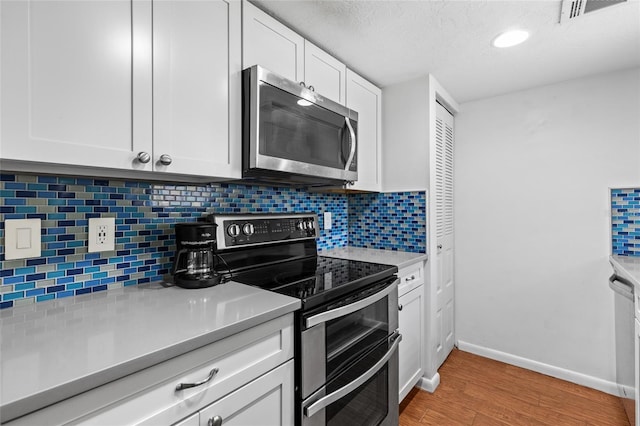 kitchen with visible vents, stainless steel appliances, light countertops, light wood-style floors, and white cabinetry