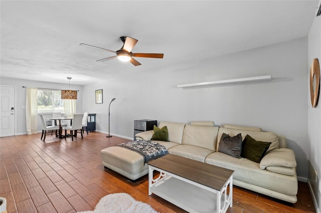 living room featuring dark wood-style floors, ceiling fan, and baseboards