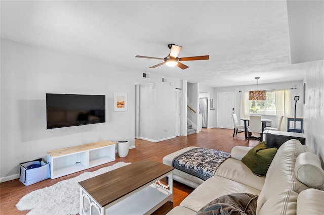 living room with baseboards, visible vents, ceiling fan, wood finished floors, and stairs