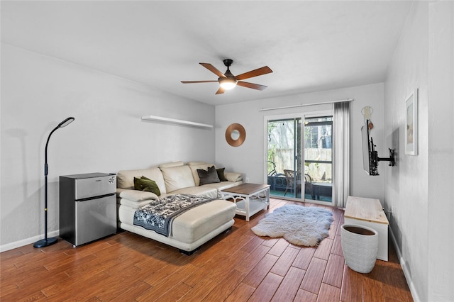 bedroom with baseboards, a ceiling fan, wood finished floors, freestanding refrigerator, and access to exterior