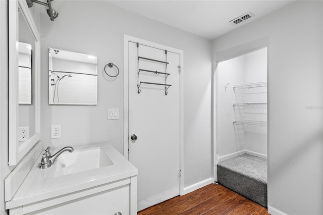 bathroom featuring visible vents, vanity, baseboards, and wood finished floors