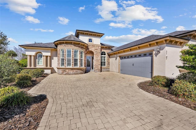 view of front of home featuring stone siding, decorative driveway, an attached garage, and stucco siding