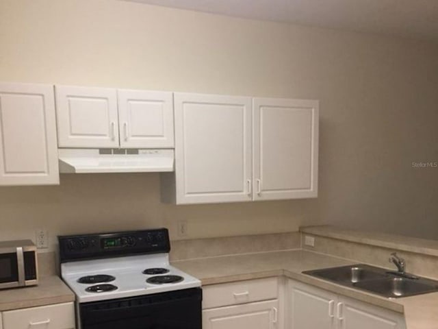 kitchen with electric range oven, stainless steel microwave, light countertops, under cabinet range hood, and white cabinetry