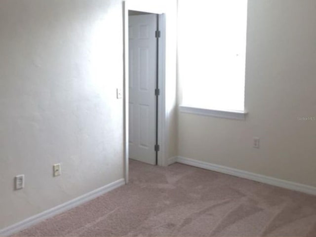 carpeted empty room with baseboards