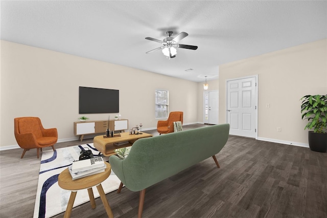 living room featuring dark wood-style floors, a textured ceiling, baseboards, and a ceiling fan