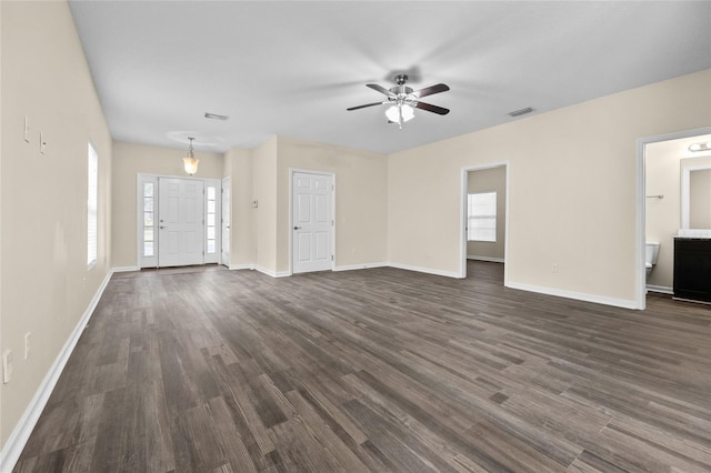 unfurnished living room featuring dark wood-style floors, visible vents, ceiling fan, and baseboards