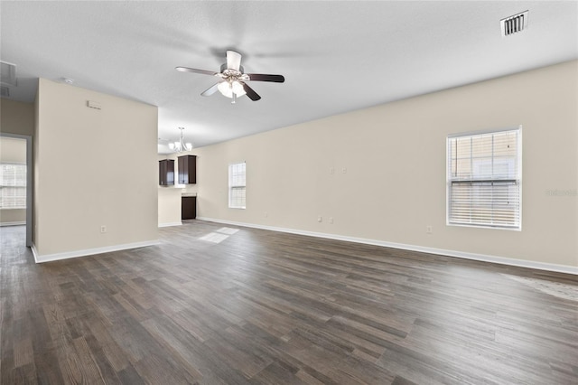 unfurnished living room featuring dark wood-style flooring, visible vents, a textured ceiling, baseboards, and ceiling fan with notable chandelier