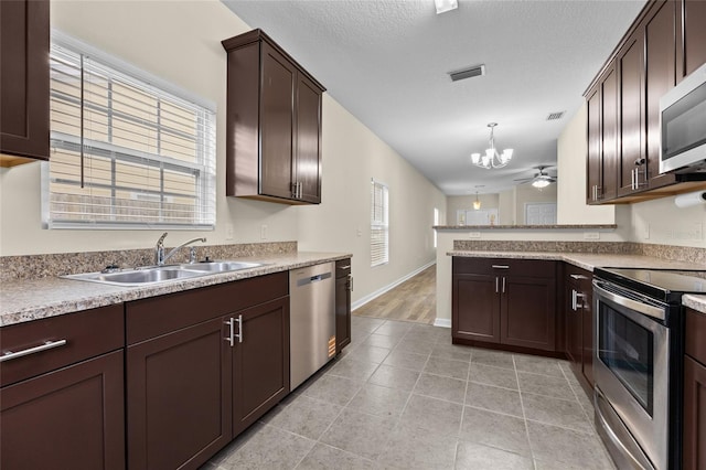 kitchen with a peninsula, a sink, light countertops, appliances with stainless steel finishes, and pendant lighting