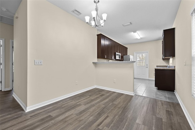 kitchen with stainless steel appliances, visible vents, dark brown cabinets, wood finished floors, and baseboards