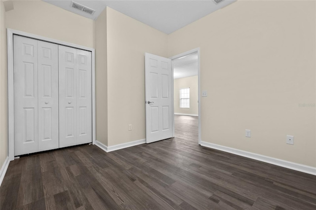 unfurnished bedroom with dark wood-style floors, visible vents, and baseboards