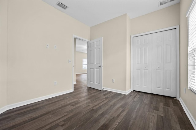 unfurnished bedroom featuring dark wood-type flooring, visible vents, and baseboards