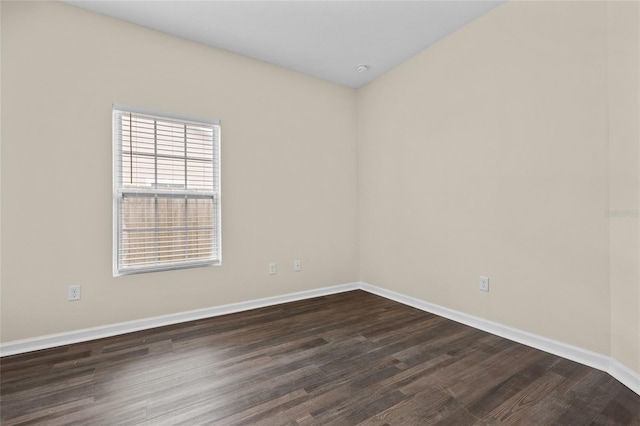 empty room with dark wood-style flooring and baseboards