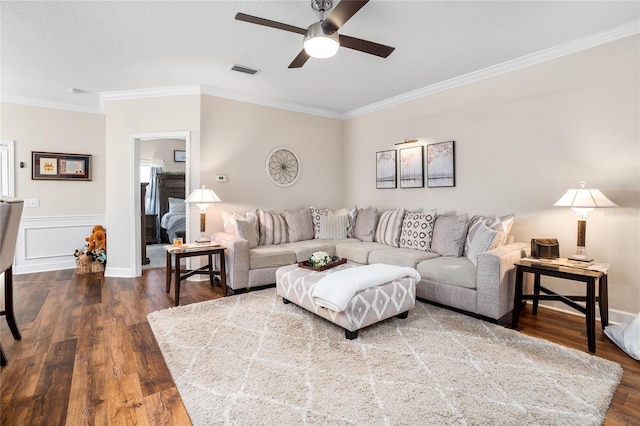 living area with dark wood-style flooring, visible vents, crown molding, and ceiling fan