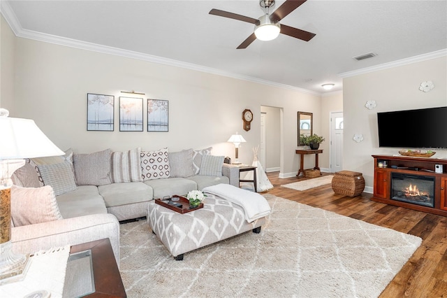 living room with ornamental molding, visible vents, baseboards, and wood finished floors