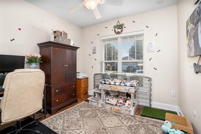 home office featuring baseboards, a ceiling fan, and wood finished floors