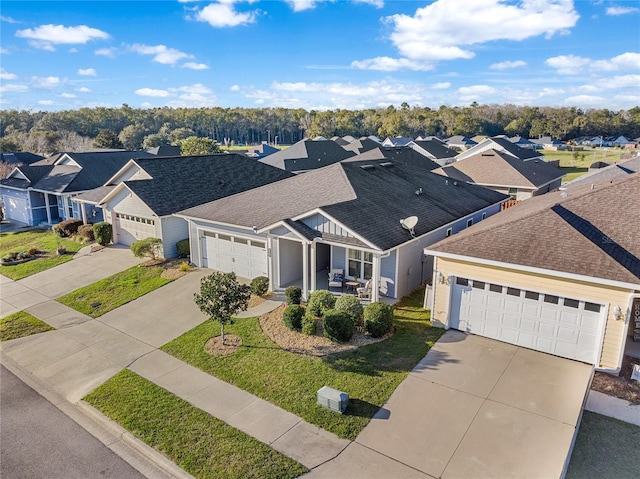 view of front of house with a shingled roof, a front yard, a garage, a residential view, and driveway