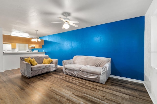 living area featuring ceiling fan with notable chandelier, baseboards, and wood finished floors