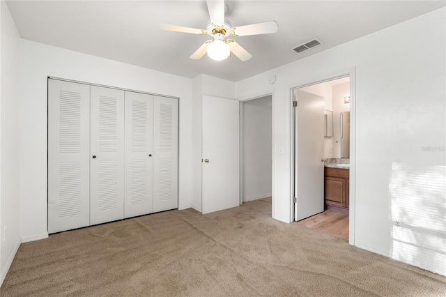 unfurnished bedroom featuring light carpet, visible vents, a ceiling fan, ensuite bath, and a closet