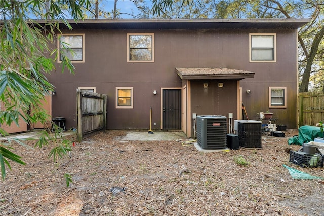 rear view of property with central AC unit, fence, and stucco siding