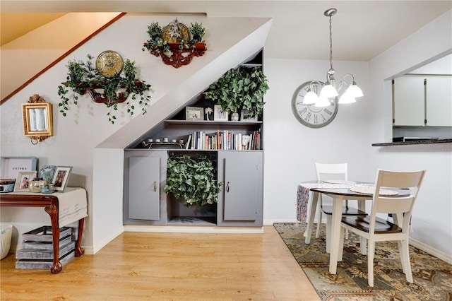 interior space featuring light wood-type flooring, decorative light fixtures, baseboards, and an inviting chandelier