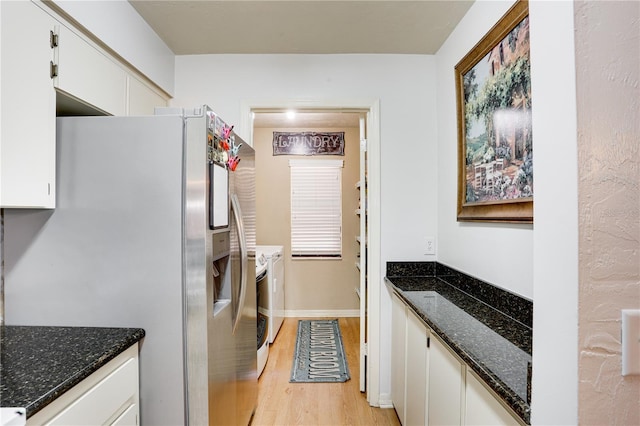 clothes washing area with light wood-type flooring, laundry area, baseboards, and washing machine and clothes dryer