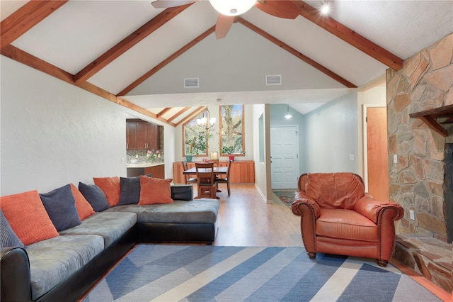 living room with visible vents, beam ceiling, ceiling fan with notable chandelier, wood finished floors, and a fireplace