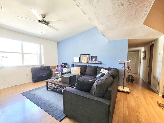 living room featuring visible vents, lofted ceiling, light wood-style floors, and ceiling fan