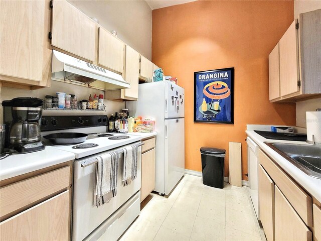 kitchen with white appliances, light countertops, under cabinet range hood, and a sink