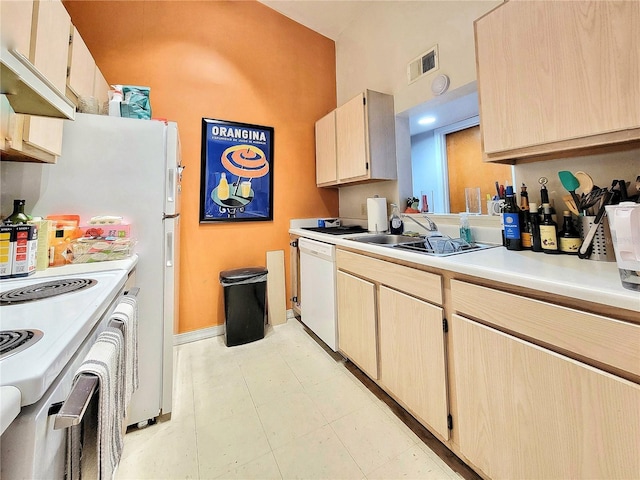 kitchen featuring white appliances, light brown cabinets, visible vents, a sink, and light countertops