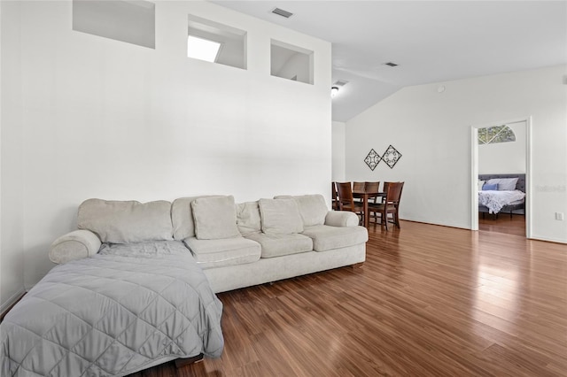 living room with vaulted ceiling, wood finished floors, and visible vents