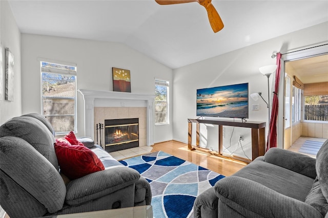 living room with a wealth of natural light, a tiled fireplace, and wood finished floors