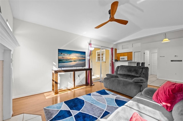 living area featuring lofted ceiling, ceiling fan, baseboards, and wood finished floors