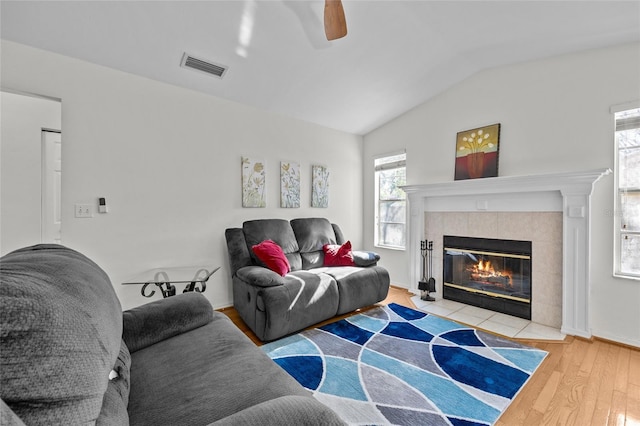 living area with lofted ceiling, plenty of natural light, wood finished floors, and visible vents