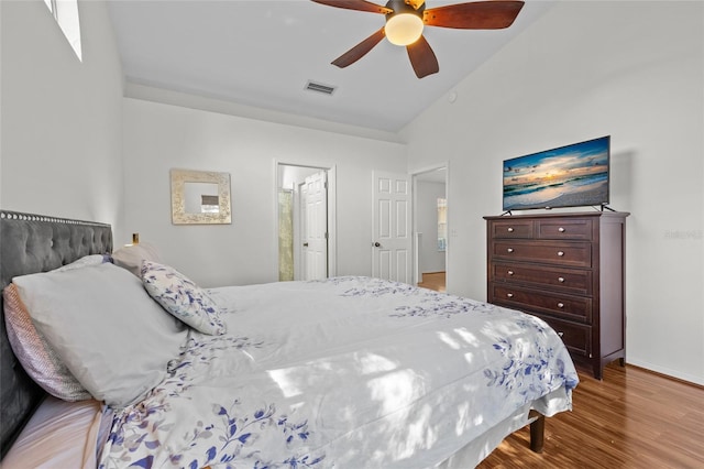 bedroom featuring a ceiling fan, visible vents, vaulted ceiling, and wood finished floors