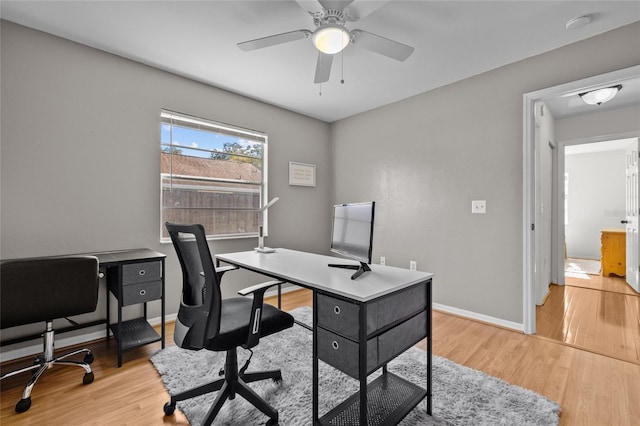 home office featuring light wood-type flooring, baseboards, and a ceiling fan