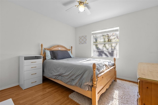 bedroom with a ceiling fan, baseboards, and light wood finished floors