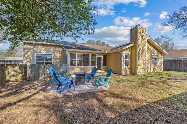 back of house featuring an outdoor fire pit, a chimney, fence, and a lawn