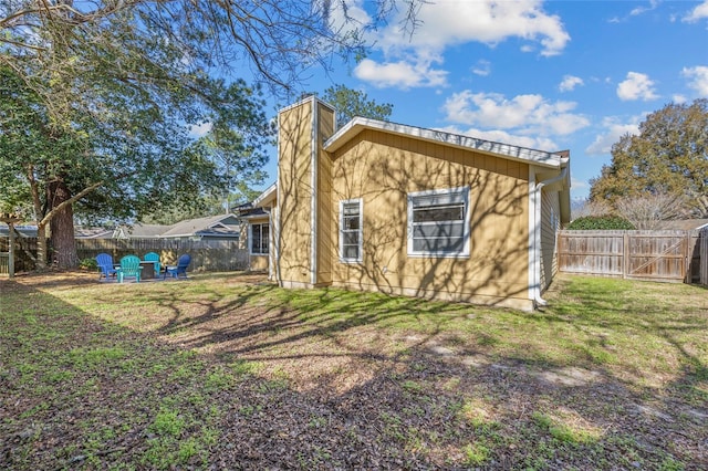 back of property featuring a fenced backyard, a chimney, and a yard