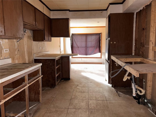 kitchen with light tile patterned floors, ornamental molding, light countertops, and dark brown cabinets