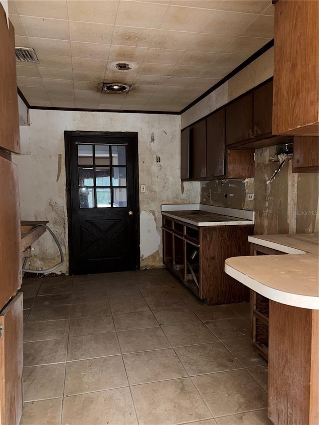 kitchen featuring light countertops, light tile patterned flooring, a peninsula, and visible vents