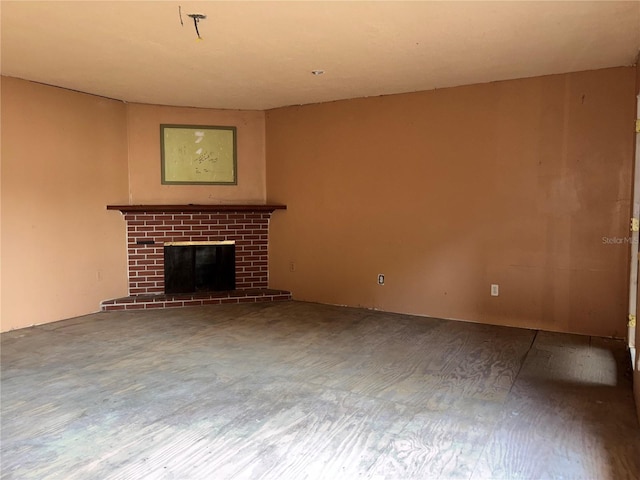 unfurnished living room featuring a brick fireplace and wood finished floors