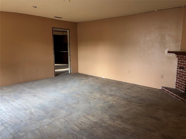 interior space featuring a brick fireplace, visible vents, and concrete flooring