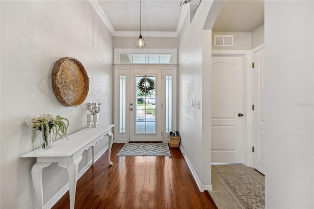 entryway featuring arched walkways, dark wood finished floors, visible vents, ornamental molding, and baseboards