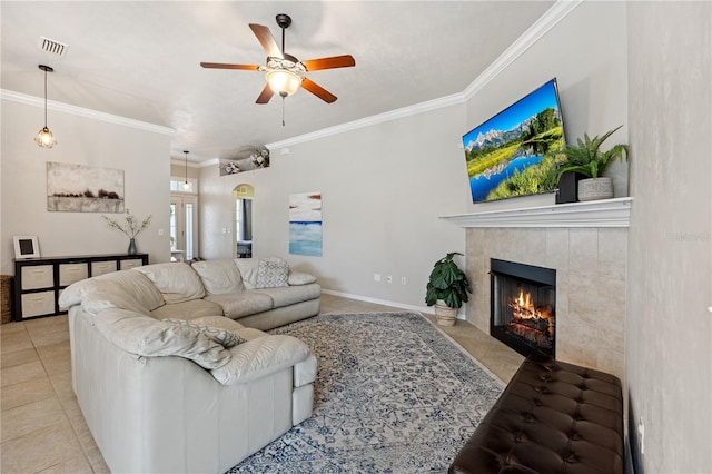 tiled living area featuring a fireplace, a ceiling fan, baseboards, visible vents, and crown molding