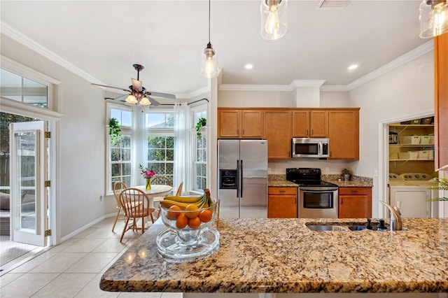 kitchen featuring brown cabinets, stainless steel appliances, crown molding, separate washer and dryer, and a sink